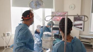 外科医生小组的后视镜是在医院手术室进行术前准备时对监视器进行检查，而男性外科医生则是用腹腔镜手术器械对病人进行手术。妇科医院.